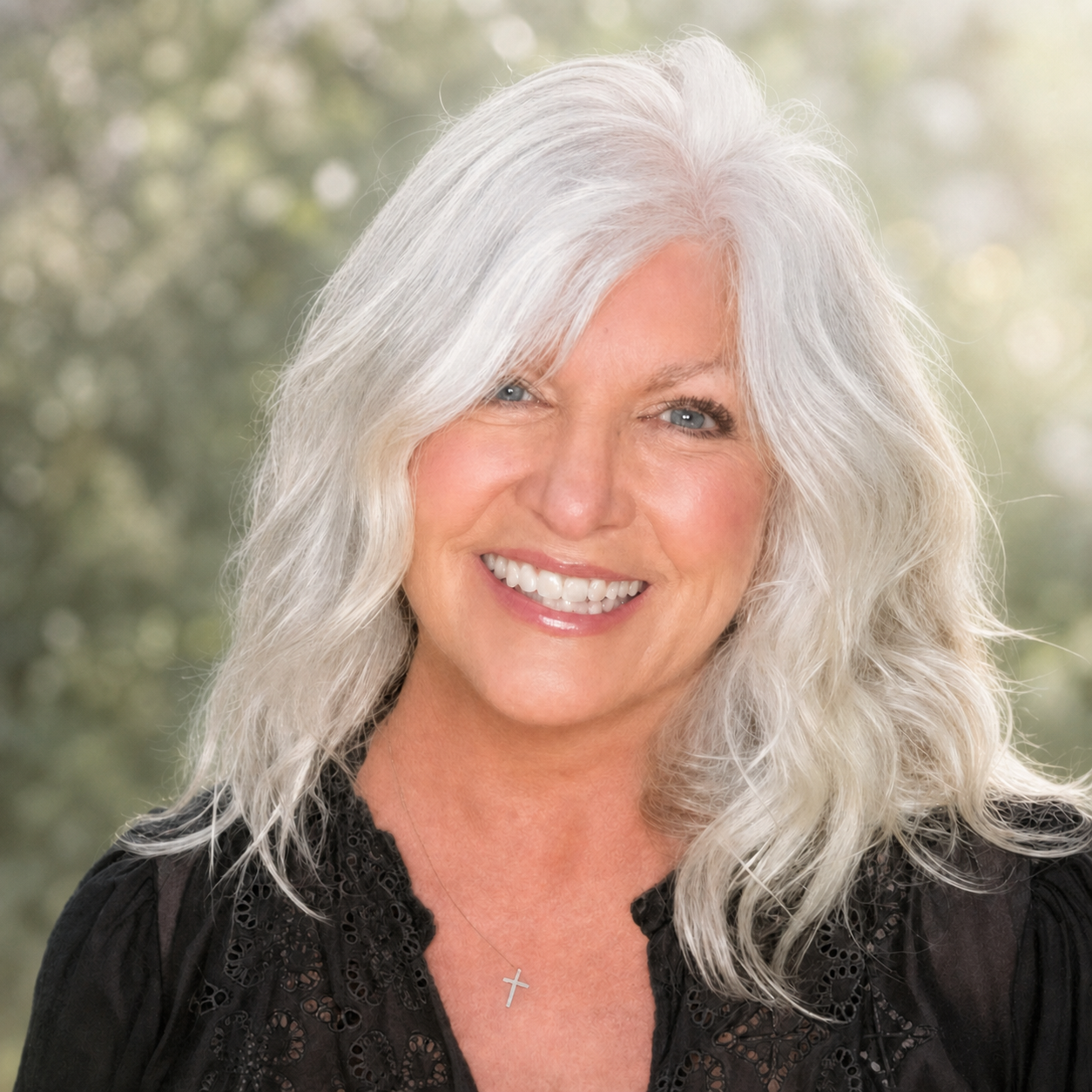 Peggy Dilley smiling against a softly lit natural background